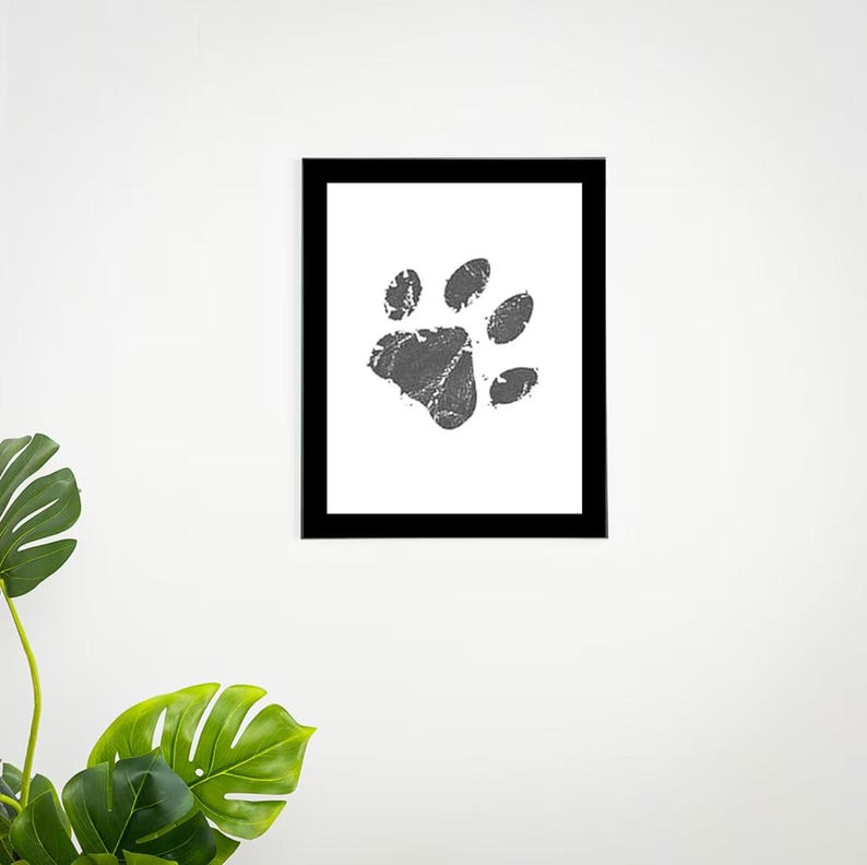 May include: Black and white framed print of a gray paw print on a white background.