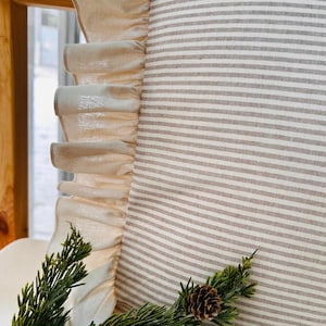 May include: A white pillow with brown stripes and a ruffled edge. The pillow is made of a soft, natural fabric and is perfect for adding a touch of farmhouse style to your home.