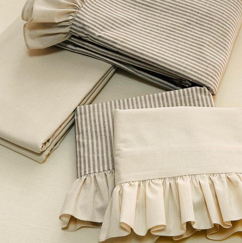 May include: Set of four cream-colored pillowcases with a gray and white striped pattern and a ruffled edge.