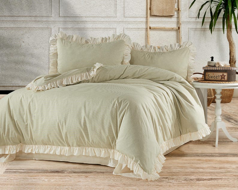 May include: A green and white striped duvet cover with a white ruffle trim. The duvet cover is on a bed with two matching pillowcases.