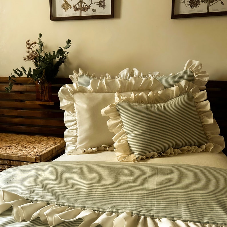 May include: A bed with a white and green striped duvet cover and a white and green striped pillow. The bed has a white ruffle around the edge of the duvet cover. The pillows are also ruffled.
