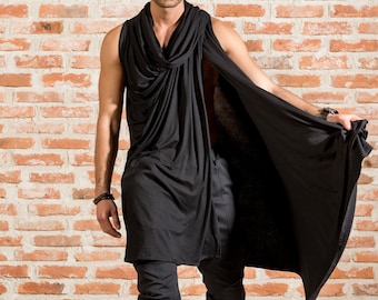 Puede incluir: Una camiseta negra sin mangas con un cuello de pico drapeado y una capa larga y fluida. La camiseta está hecha de una tela suave y elástica y tiene un ajuste holgado. El modelo lleva pantalones negros y zapatos negros.