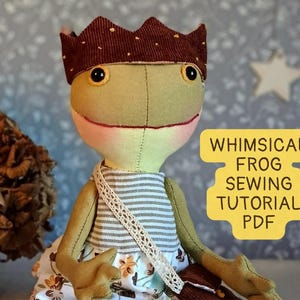 May include: A stuffed frog doll wearing a brown corduroy crown with small yellow dots, a grey and white striped top, and a floral skirt. A white lace strap crosses the chest. Text on the right reads: WHIMSICAL FROG SEWING TUTORIAL PDF.
