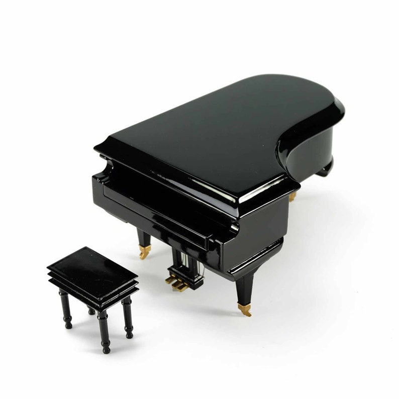 Pode incluir: Um piano de cauda preto com um banquinho de piano preto correspondente. O piano tem detalhes dourados nas teclas e nas pernas.