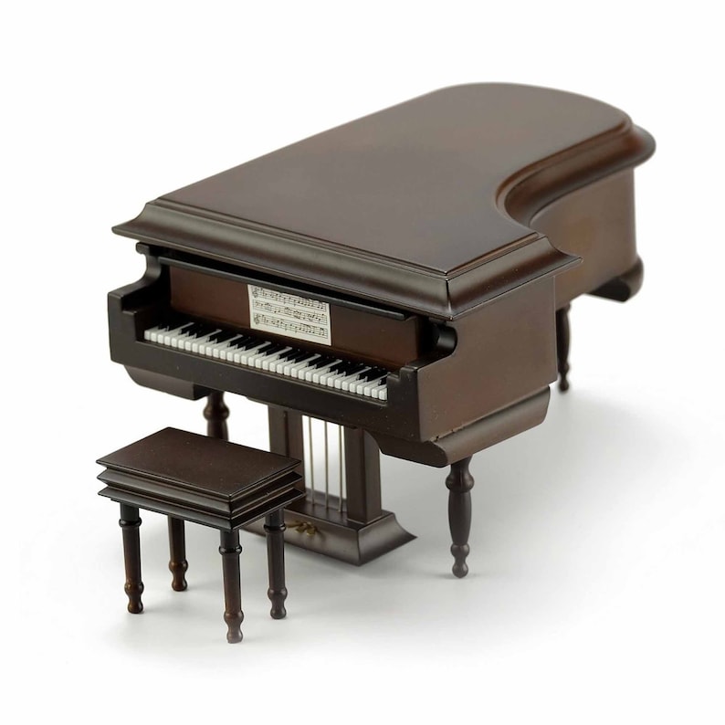 May include: A dark brown wooden grand piano with a matching stool. The piano has a white keyboard and a music sheet on the top.