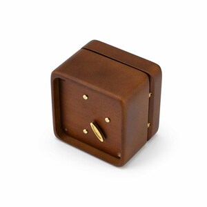 May include: A small, wooden music box with a brown finish. The box has a crank on the top and a small, brass-colored keyhole on the side.