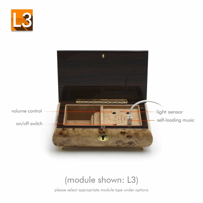 May include: A wooden music box with a brown lid and a light wood interior. The box has a volume control knob, an on/off switch, a light sensor, and a USB port for self-loading music. The text "(module shown: L3)" and "please select appropriate module type under options" is printed below the box.
