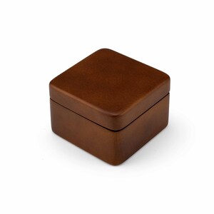 May include: A small, square wooden box with a brown finish. The box is closed and has a smooth, polished surface.