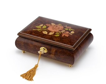May include: A wooden music box with a floral inlay design. The box has a gold-colored keyhole and a tassel.