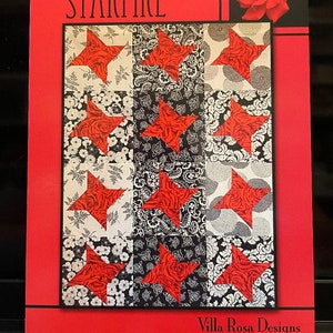 May include: A quilting pattern titled "Starfire" by Villa Rosa Designs. The pattern features a quilt block design with red stars on a black and white background.