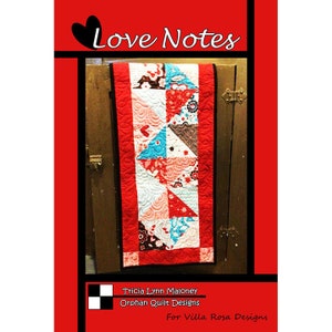 May include: A red, white, and blue patchwork table runner with a heart design. The table runner is titled "Love Notes" and is by Tricia Lynn Maloney, Orphan Quilt Designs for Villa Rosa Designs.