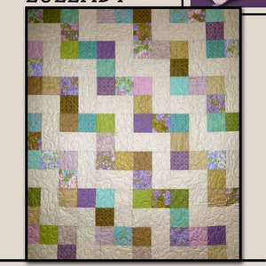 May include: A patchwork quilt with the word "LULLABY" at the top. The quilt features squares of various colors, including green, purple, blue, and pink, arranged in a geometric pattern. The quilt is on a cream background with a floral design.