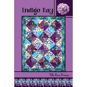 May include: Indigo Bay quilt pattern featuring a purple and blue patchwork design with a floral print. The pattern is surrounded by a purple border and a floral border. The text "Indigo Bay" and "Villa Rosa Designs" are printed on the pattern.