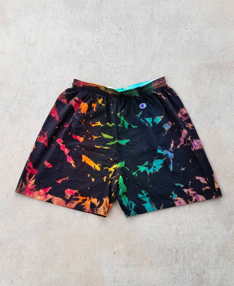 May include: Black tie-dye shorts with a rainbow pattern and a small white Champion logo on the left side.