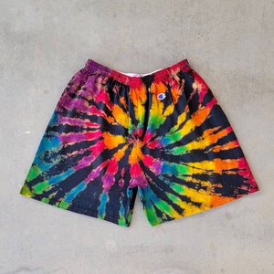 May include: Black tie-dye shorts with a rainbow swirl pattern and a small white Champion logo on the left side.