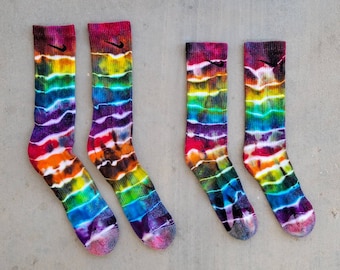 May include: Four pairs of colorful tie-dye socks with a black Nike swoosh logo. The socks are in various shades of blue, green, purple, orange, and yellow.