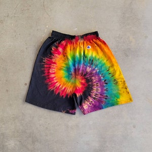 May include: Black tie-dye shorts with a rainbow swirl pattern and a small white Champion logo on the waistband.