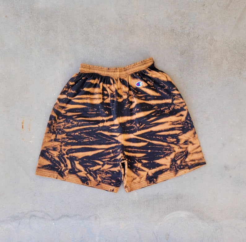 May include: Black and brown tie-dye shorts with a white Champion logo on the left side.