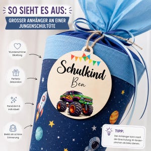 Pode incluir: Um cone escolar azul marinho com uma borda azul clara e uma etiqueta de madeira. A etiqueta diz "Schulkind Ben" e apresenta uma ilustra&ccedil;&atilde;o de um caminh&atilde;o monstro verde. O cone &eacute; decorado com estrelas, planetas e um foguete.
