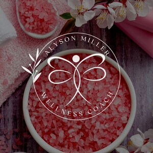 K&ouml;nnte beinhalten: Ein Bild zum Thema Spa mit einem wei&szlig;en Logo mit der Aufschrift "ALYSON MILLER WELLNESS COACH" in einem kreisf&ouml;rmigen Design. Das Logo befindet sich vor einem Hintergrund aus rosa Badesalzen, Handt&uuml;chern und Blumen, was eine ruhige und einladende Atmosph&auml;re schafft.