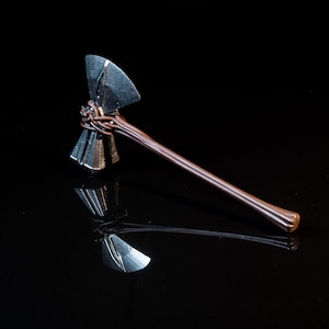 May include: A silver axe with a brown wooden handle. The axe head has a unique design with multiple blades.