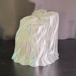 Può includere: Un vaso trasparente in plastica stampato in 3D con un design a tronco d'albero. Il vaso ha quattro aperture nella parte superiore, perfette per contenere fiori o altri oggetti decorativi.