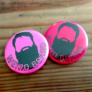May include: Two pink and black button pins with the text "Weird Beard" and a silhouette of a person with a beard.