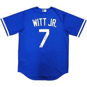 May include: Royal blue baseball jersey with white lettering and the name "WITT JR." and the number "7". The jersey has white stripes on the sleeves and a small logo on the upper chest.