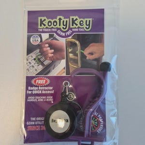 May include: A purple and black "Kooty Key" germ-free hand tool in a clear plastic package. The package includes a badge retractor for quick access and text that reads "Avoid touching door handles, ATMs & more!"