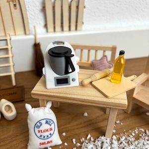 Könnte beinhalten: Ein Miniatur-Küchenset mit einem weißen Standmixer, einem Holz-Nudelholz, einem Schneidebrett, einer Ölflasche und einem Sack Mehl mit der Aufschrift "Old Mill Flour 50 LBS".