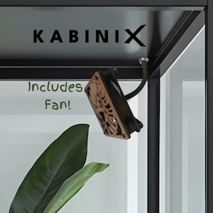 Könnte beinhalten: Eine schwarze und transparente Vitrine mit dem Text "KABINIX" und "Includes Fan!". Ein dekorativer Ventilator ist im Inneren des Gehäuses montiert. Ein großes grünes Blatt ist im Vordergrund zu sehen.