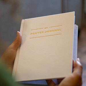 Puede incluir: Un diario de oraci&oacute;n blanco con letras doradas que dicen "My Prayer Journal".