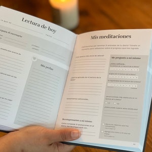 May include: A black and gray journal with the Spanish words "Lectura de hoy" and "Mis meditaciones" on the cover. The journal is open to a page with the headings "Prepara el escenario", "Mis perlas", "Me pregunto a mi mismo", and "Recompensarme a mi mismo".