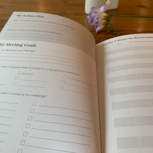 May include: A white planner with a black and gray design. The planner has sections for "My Action Plan", "My Meeting Goals", and "Gems I Want to Remember".