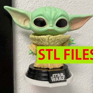 Könnte beinhalten: Eine grüne und braune Star Wars-Figur von Baby Yoda, auch bekannt als The Child, aus der Disney+-Serie The Mandalorian. Die Figur steht auf einem schwarzen Sockel mit dem Aufdruck "Star Wars". STL FILES ist in roten Buchstaben auf grünem Hintergrund gedruckt.