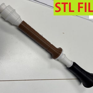 Op de afbeelding: Een 3D-geprinte bruine en witte toverstaf met een zwarte punt. STL FILES staat in groene tekst op de achtergrond.