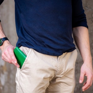 Pode incluir: Uma pessoa vestindo uma camisa azul e cal&ccedil;as c&aacute;qui com uma carteira verde no bolso de tr&aacute;s.