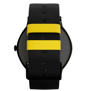 May include: Black leather watch with a yellow stripe on the strap. The watch face is black and round.