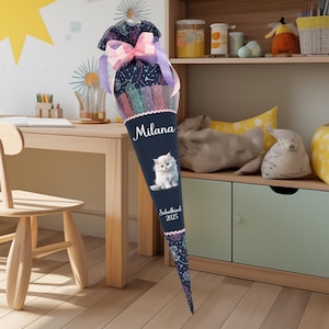 May include: A blue and pink school cone with a white kitten illustration, the text "Milana" and "Schulkind 2025".