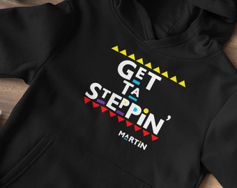 Op de afbeelding: Zwarte hoodie met een kleurrijke afbeelding met de tekst "Get Ta Steppin' Martin".
