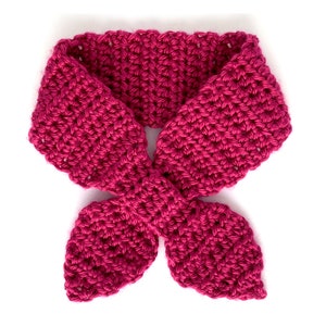 May include: A pink crocheted neck scarf with a bow tie design.