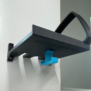 Puede incluir: Una estanter&iacute;a de pared negra con un gancho azul. La estanter&iacute;a tiene un asa y el texto "DEDICATED SOLUTIONS" impreso en ella.