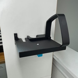 Puede incluir: Un estante de pared negro con un asa. El estante est&aacute; hecho de pl&aacute;stico y tiene una superficie texturizada.