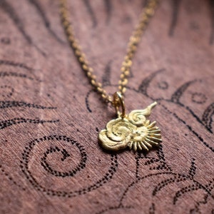 Op de afbeelding: Een gouden ketting met een hanger in de vorm van een zon en wolken. De hanger is gedetailleerd met draaiende lijnen en een zonnestralenontwerp.