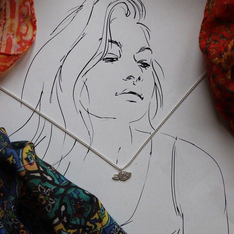 May include: A line drawing of a woman with long hair wearing a silver chain necklace with a small cloud pendant.