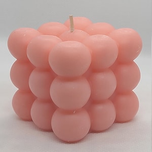 May include: A pink bubble candle with a square shape and a single wick.