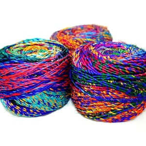May include: Three balls of colorful yarn, each with a different mix of colors, including red, blue, green, yellow, and orange. The yarn is made of a variety of materials, including silk and cotton.