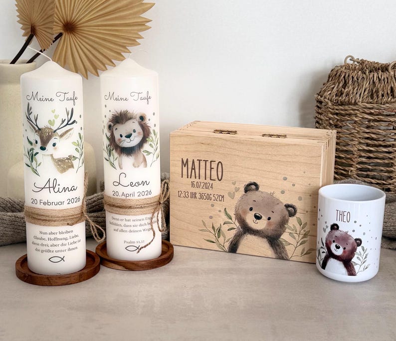 Pu&ograve; includere: Due candele cilindriche bianche con spago, ciascuna con un'illustrazione di animale, il testo Meine Taufe, un nome e una data. Una scatola rettangolare in legno con l'illustrazione di un orso e il nome Matteo, e una tazza bianca con un orso e il nome Theo.