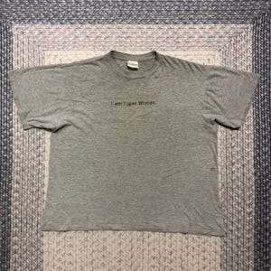 Puede incluir: Una camiseta gris con el texto "I am Tiger Woods." impreso en la parte delantera.
