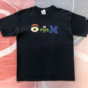 May include: Black t-shirt with a graphic design featuring an eye, a bee, and the letters "IBM" in colourful letters. The shirt has short sleeves and a crew neck. The shirt is made of a soft material.